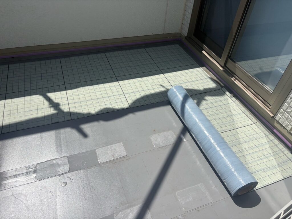 【ベランダ防水】<br />
自着シート貼り付け<br />
（既存の下地との隙間を作ってくれる通気性能シートになります。）